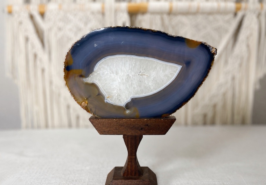 A polished agate slice displayed on a wooden stand